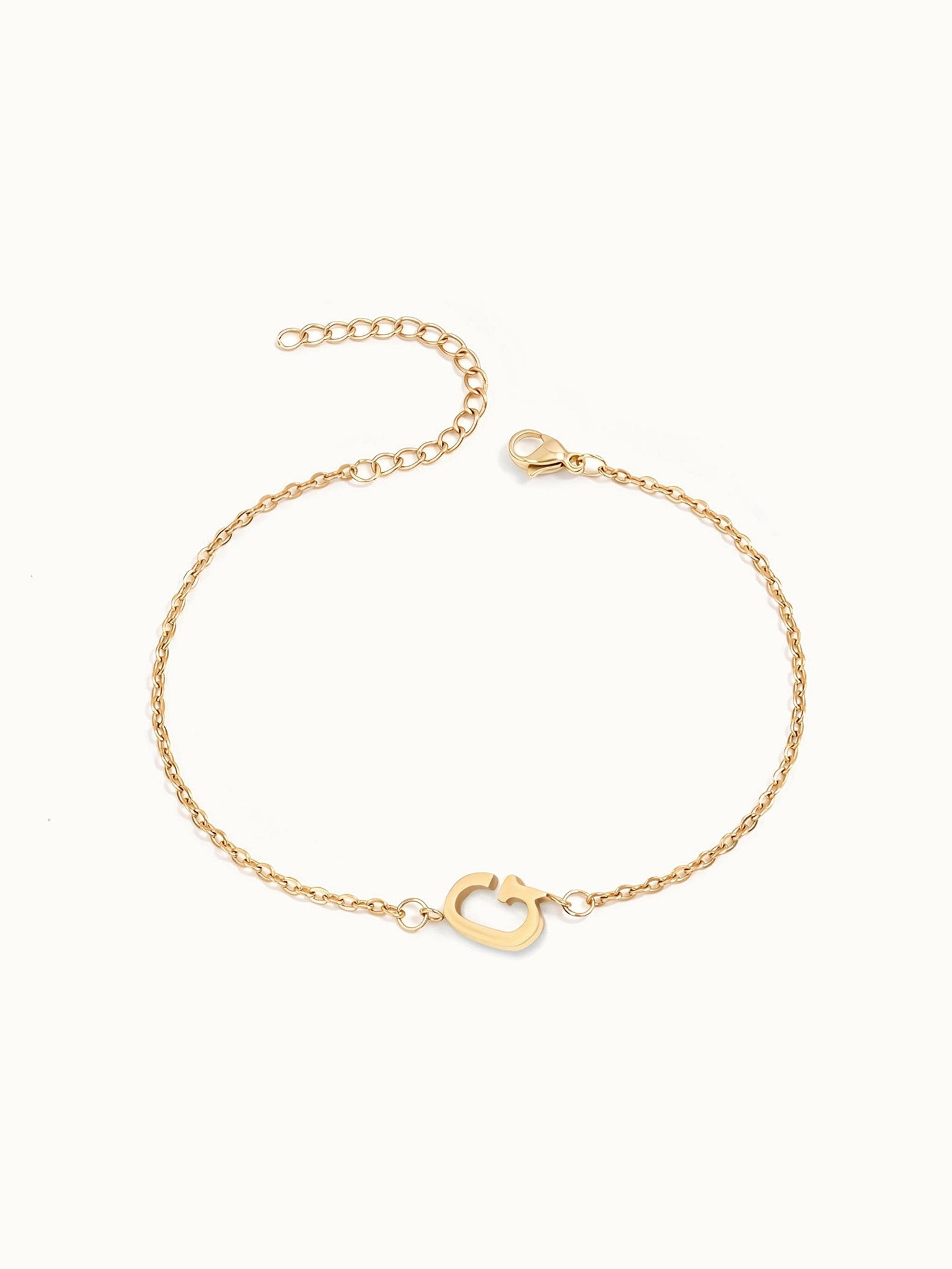 Initial Bracelet – letter G charm on a fine cable chain, gold, on ivory background
