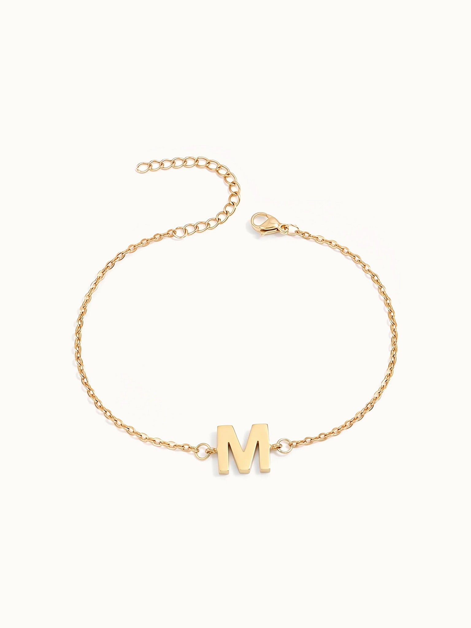 Initial Bracelet – letter M charm on a fine cable chain, gold, on ivory background