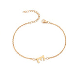 Initial Bracelet in gold with letter E charm, flat lay on white background