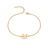 Initial Bracelet in gold with letter M charm, flat lay on white background