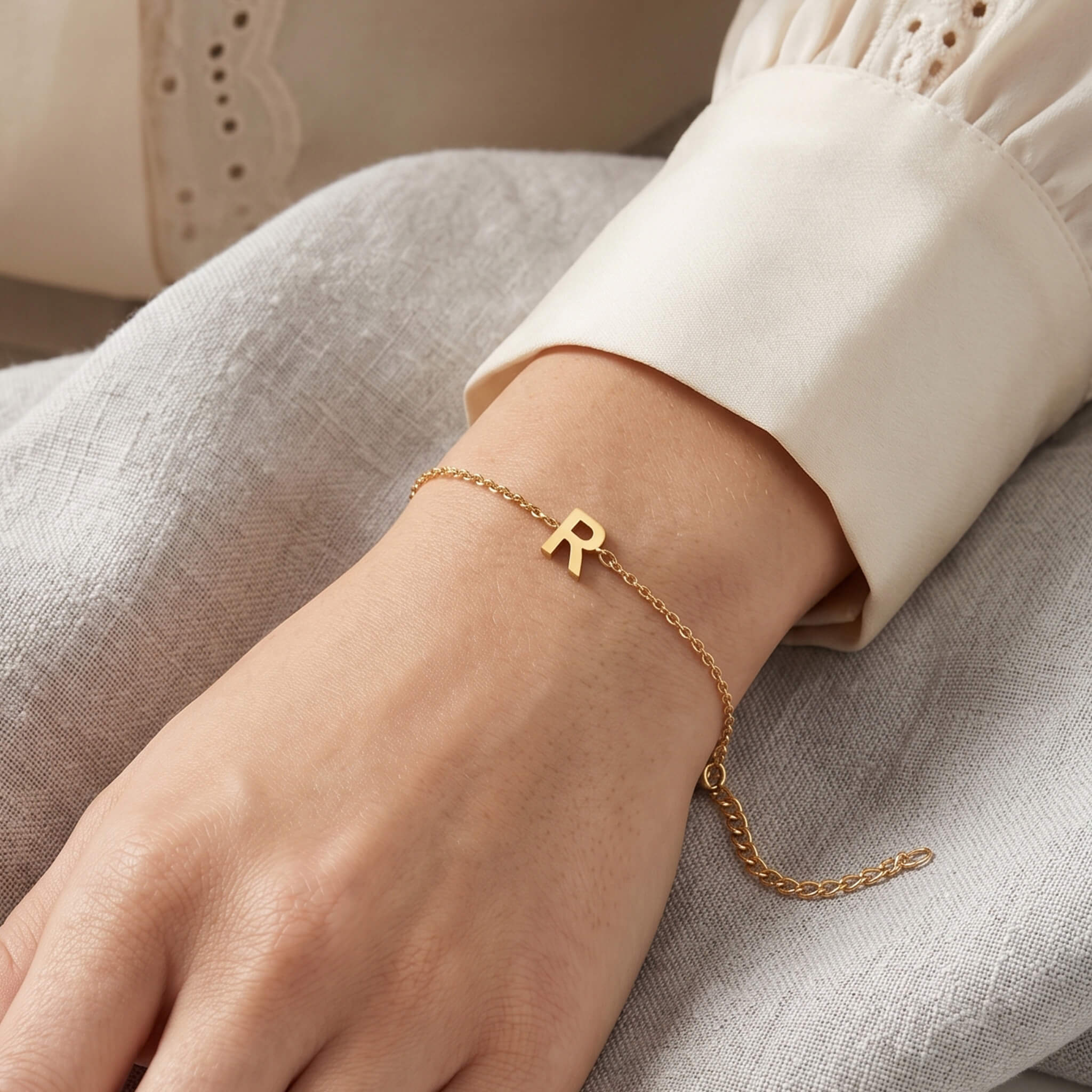Initial Bracelet in gold with letter R charm, worn on a woman's wrist