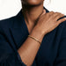 Kept Season Bangle – worn on the wrist, hand resting on the shoulder, gold, dark blazer, ivory studio background