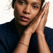 Kept Season Bangle – worn on the wrist, hands pressed together beside the face, gold, dark blazer, ivory studio background