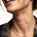 Kindred Link Necklace – worn at the collarbone, laughing, gold, navy blazer, ivory studio background