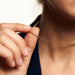 Kindred Link Necklace – fingers pinching the chain near the neck, close crop, gold, navy blazer, ivory studio background