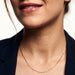 Kindred Link Necklace – worn at the collarbone, smiling, gold, navy blazer, ivory studio background