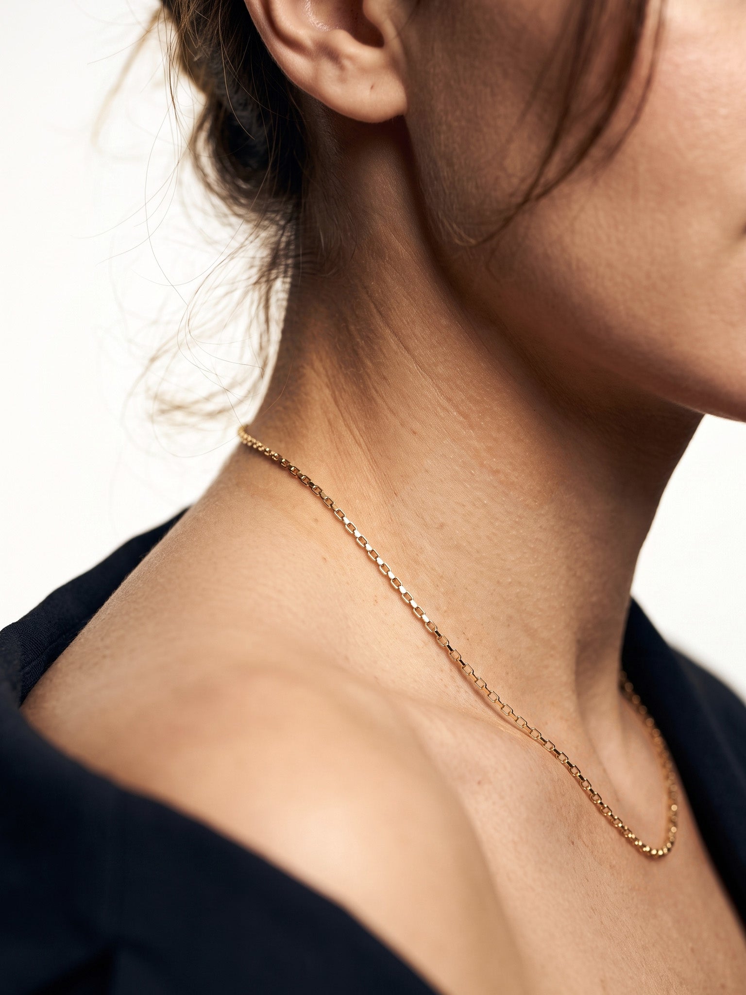 Kindred Link Necklace – worn along the collarbone, side view of neck and shoulder, gold, navy blazer, ivory studio background