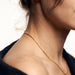 Kindred Link Necklace – worn along the collarbone, side view of neck and shoulder, gold, navy blazer, ivory studio background