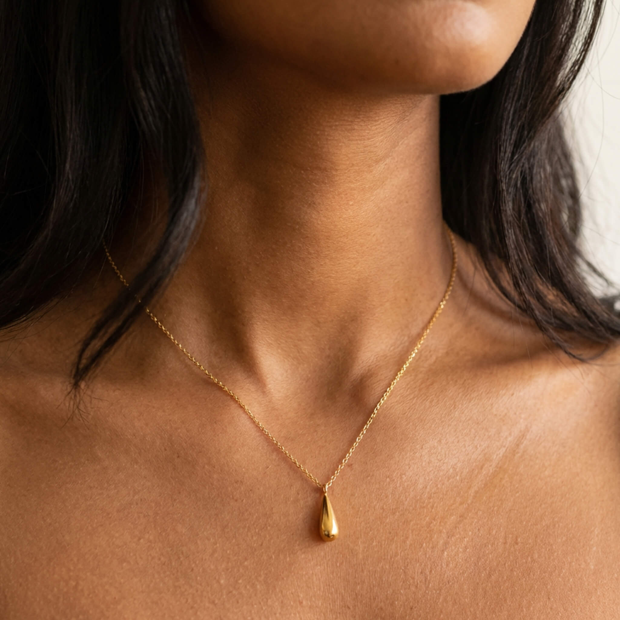Mercy Teardrop Necklace in gold worn against a woman's collarbone