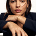 Morning Light Twist Bracelet – worn on the wrist, chin resting on folded arms, gold, dark blazer, ivory studio background