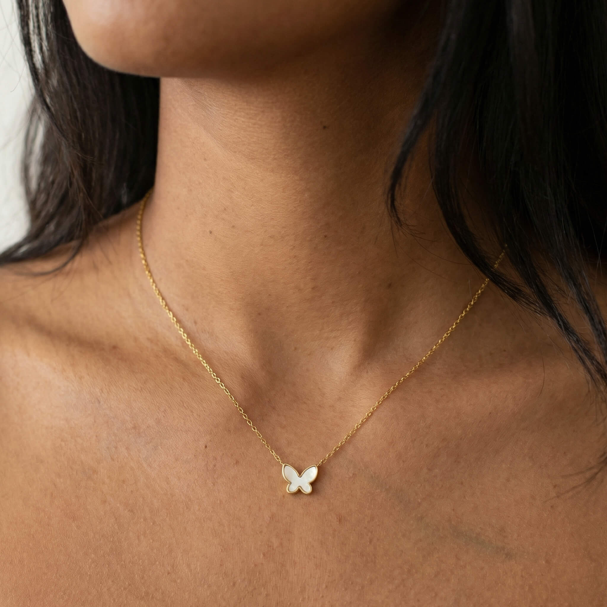 New Season Butterfly Necklace worn on a woman's neck, gold chain with pearl butterfly