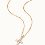 Radiant Cross Necklace in gold, lying flat with the chain in a curve