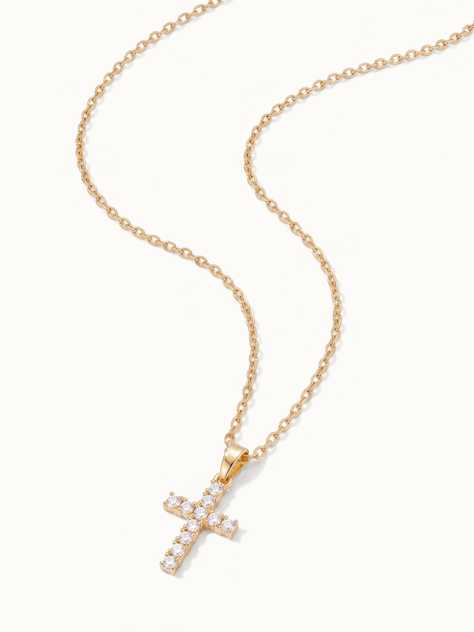 Radiant Cross Necklace in gold, lying flat with the chain in a curve