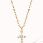 Radiant Cross Necklace in gold, hanging on a fine chain, with a long shadow