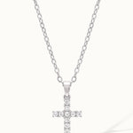 Radiant Cross Necklace in silver, hanging on a fine chain, with a long shadow