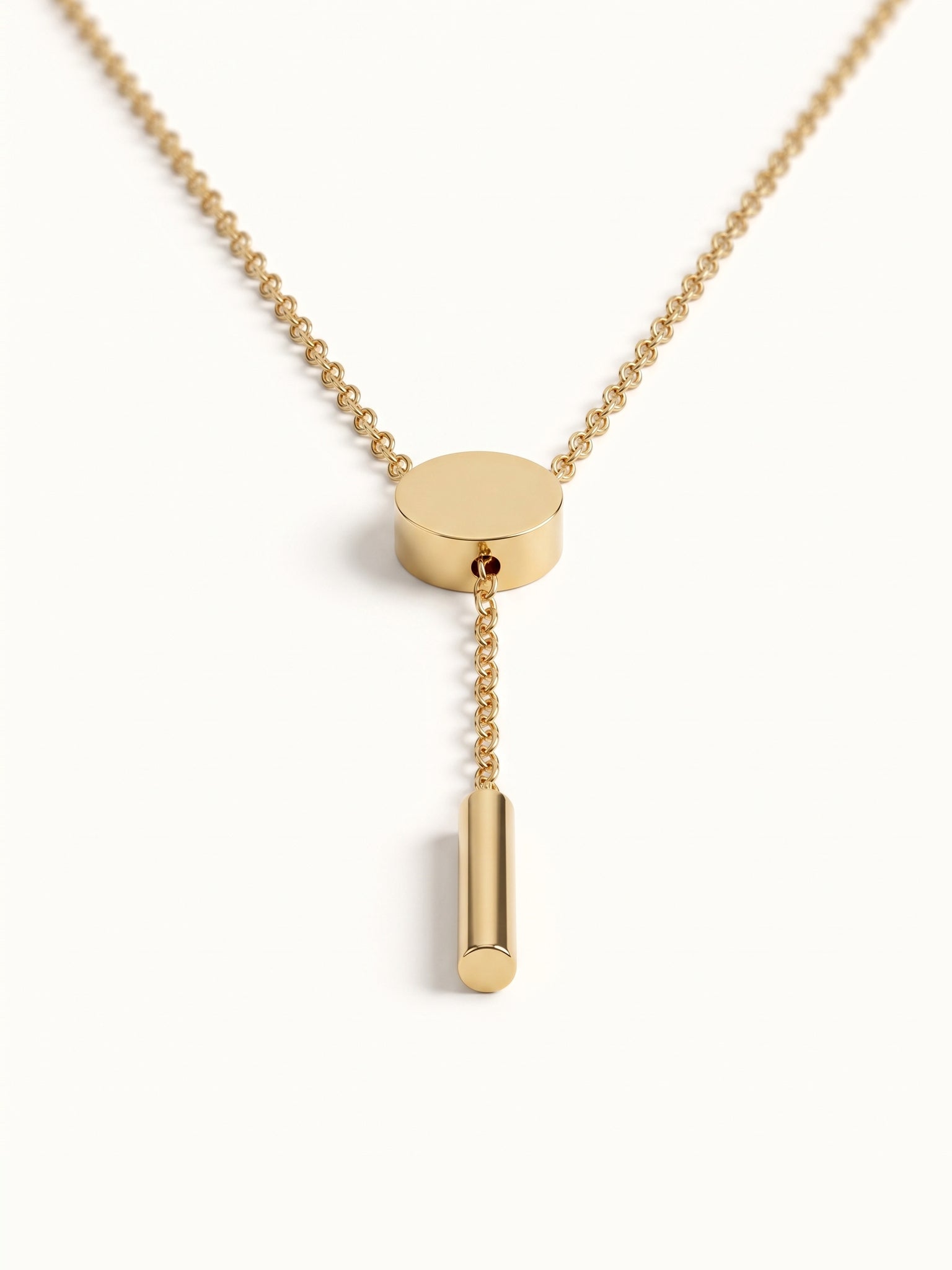 Rising Lariat Necklace – lariat hanging straight with disc slider and bar drop, gold, on ivory background