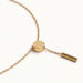 Rising Lariat Necklace – lariat laid in a curve with disc slider and bar drop, gold, on ivory background