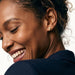 Rooted Cross Studs – worn in the ear, laughing with eyes closed and head tilted down, gold cross stud, curly hair up