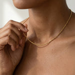 Rooted Rope Chain Necklace – worn at the collarbone, hand touching the chain, gold, bare neckline