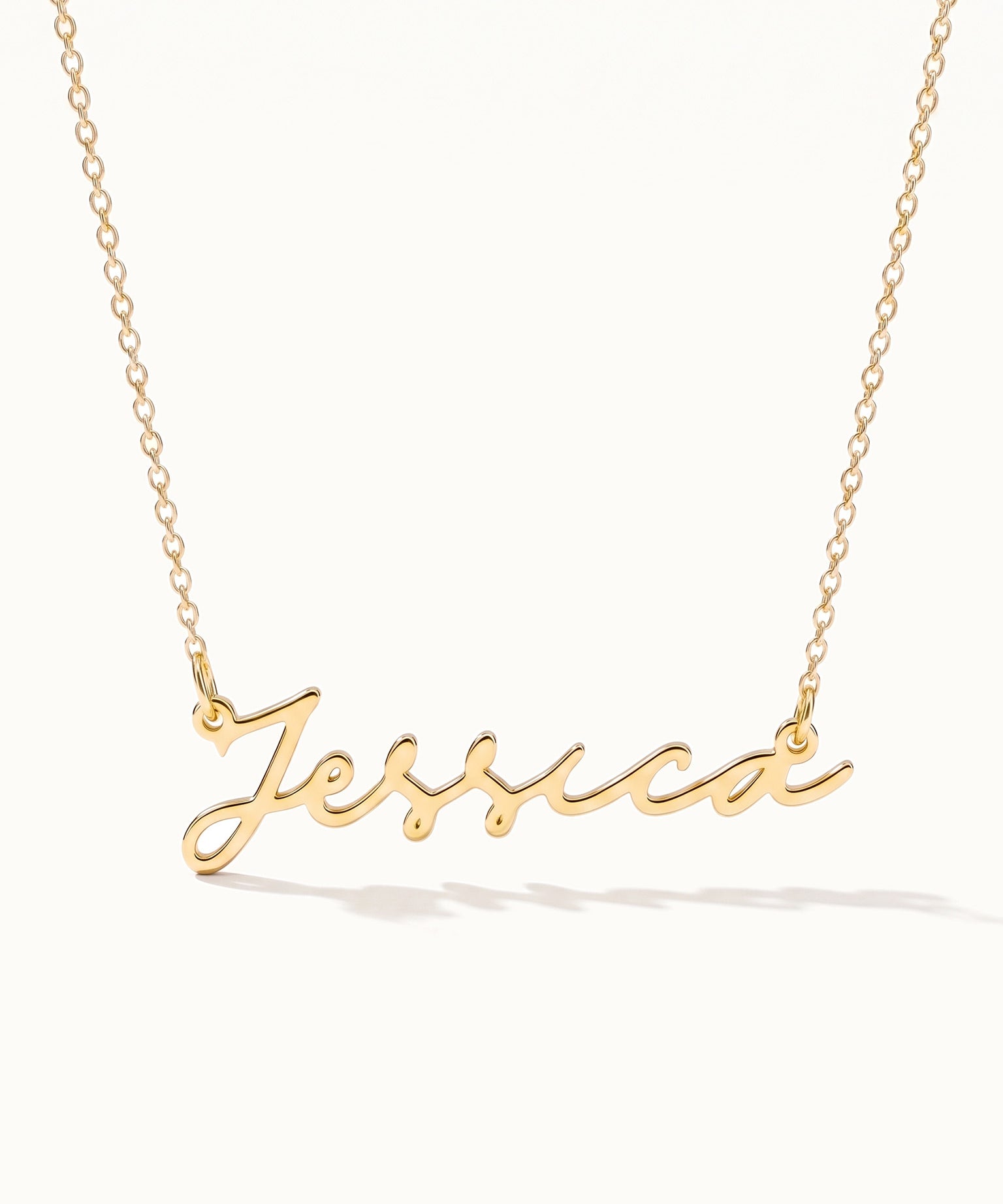 Signature Name Necklace – name "Jessica" in script hanging on a fine chain, closer view, gold, on ivory background