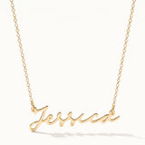 Signature Name Necklace – name "Jessica" in script hanging on a fine chain, gold, on ivory background