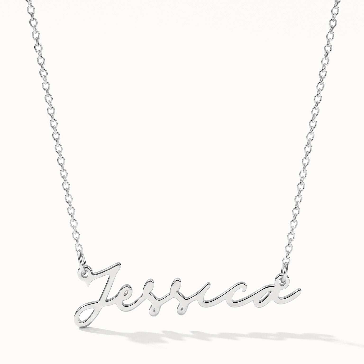 Signature Name Necklace – name "Jessica" in script hanging on a fine chain, silver, on ivory background