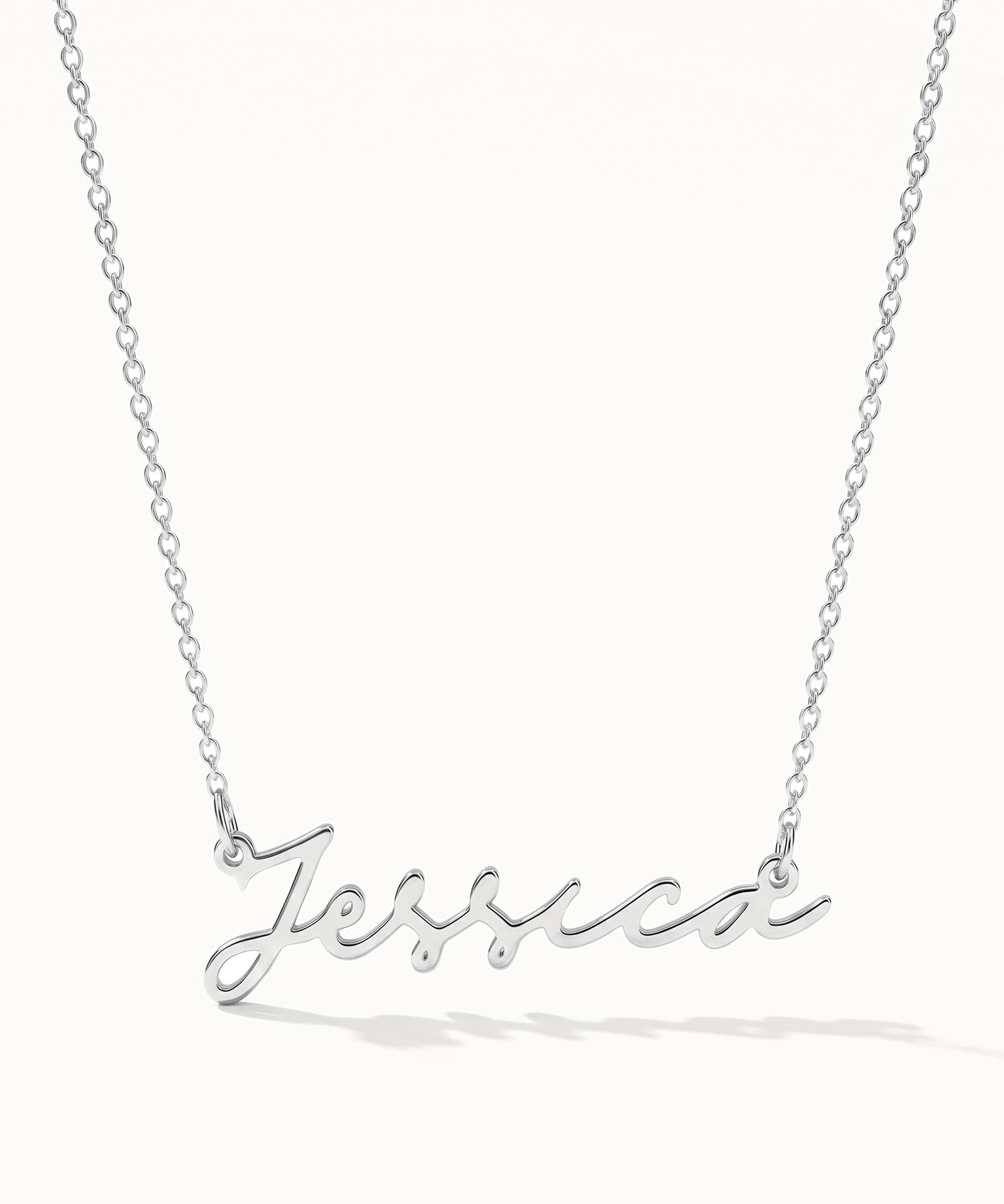 Signature Name Necklace – name "Jessica" in script hanging on a fine chain, silver, on ivory background