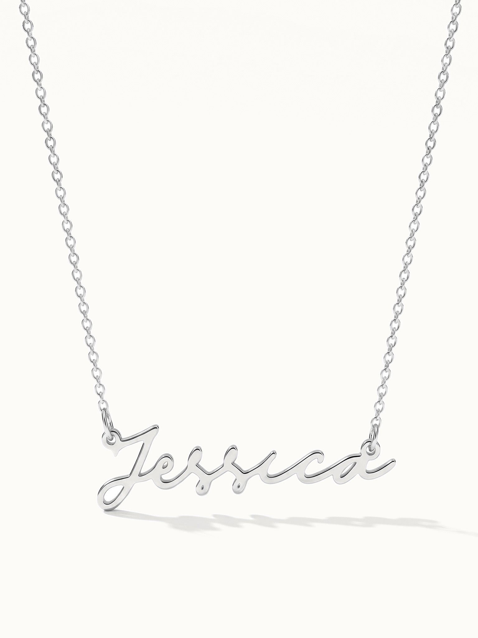 Signature Name Necklace – name "Jessica" in script hanging on a fine chain, silver, on ivory background