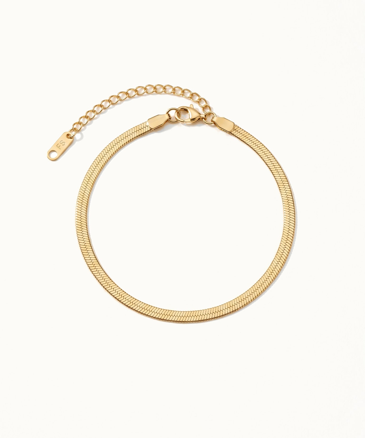 Still Waters Herringbone Bracelet – laid in a circle, seen from above, gold, on ivory background