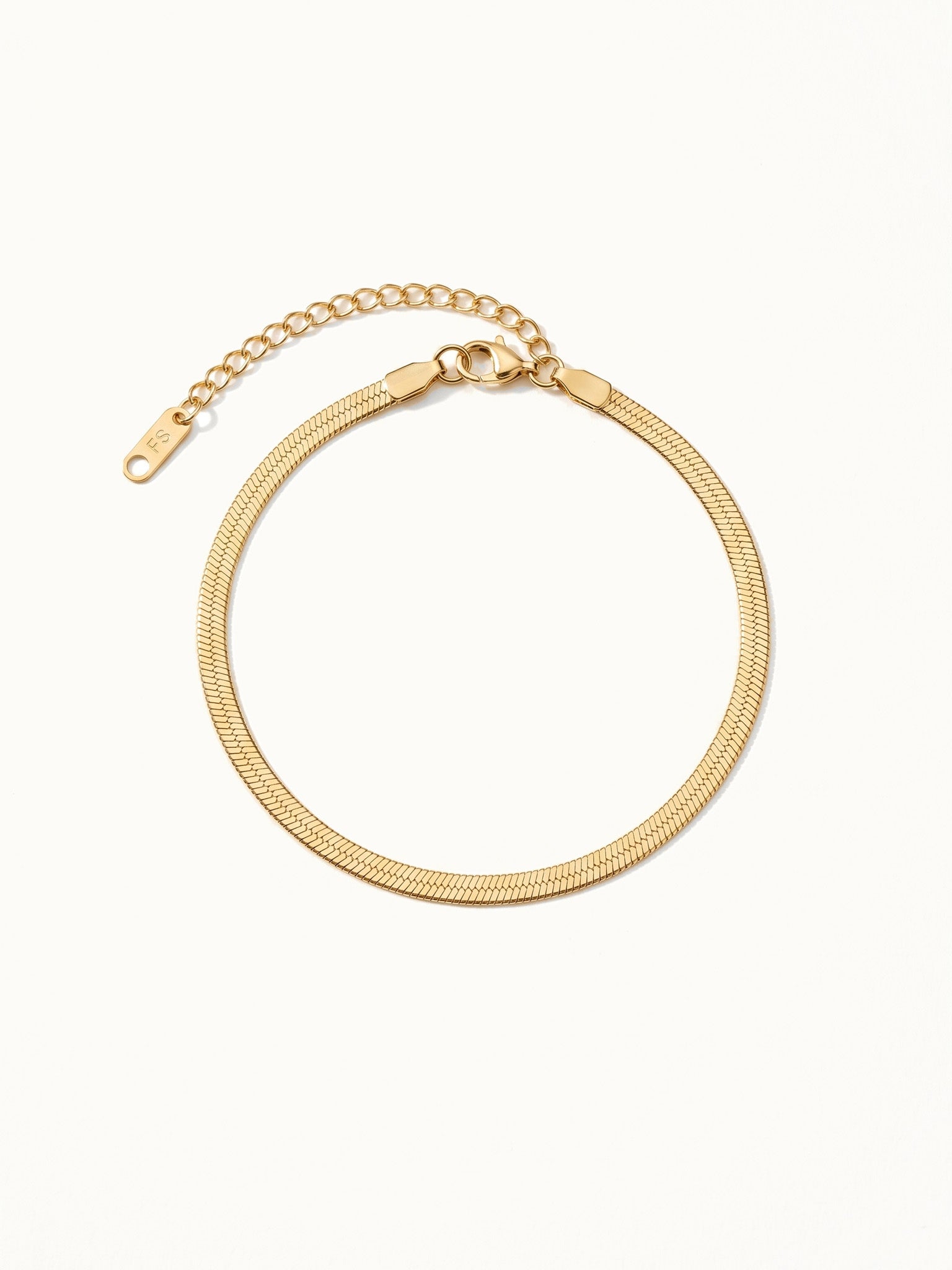 Still Waters Herringbone Bracelet – laid in a circle, seen from above, gold, on ivory background