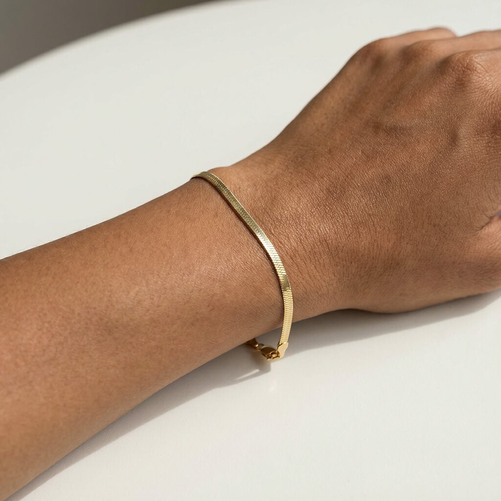 Still Waters Herringbone Bracelet – worn on the wrist in soft sunlight, gold, on a pale table