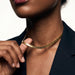 Fallen Herringbone Necklace – fingers lifting the herringbone chain at the neck, gold, black blazer, ivory studio background