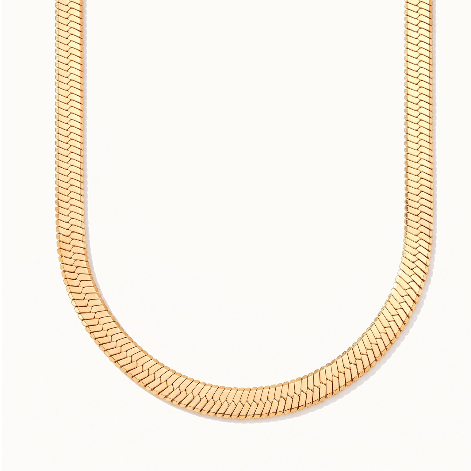 Sunday Best Herringbone Necklace – wide flat herringbone chain hanging in a drop, gold, on ivory background
