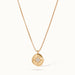 True North Necklace – star-compass medallion hanging on a box chain, gold, on ivory background