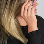 Two Paths Ring – worn with a hand at the temple, gold, black top, grey background