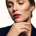 Whisper Band Ring – worn on a hand resting beneath the chin, gold, dark blazer, ivory studio background