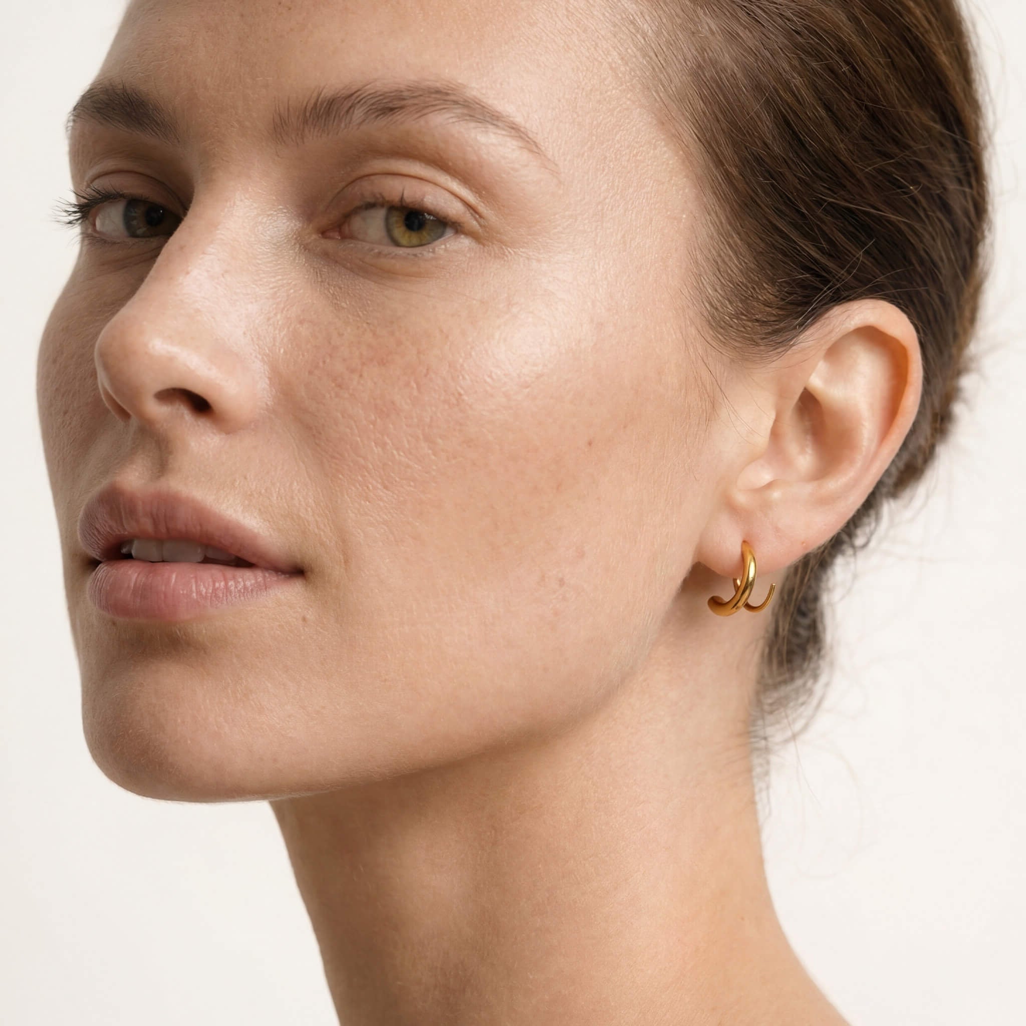 Whisper Hoops – worn in the ear, three-quarter face view, gold, hair tied back