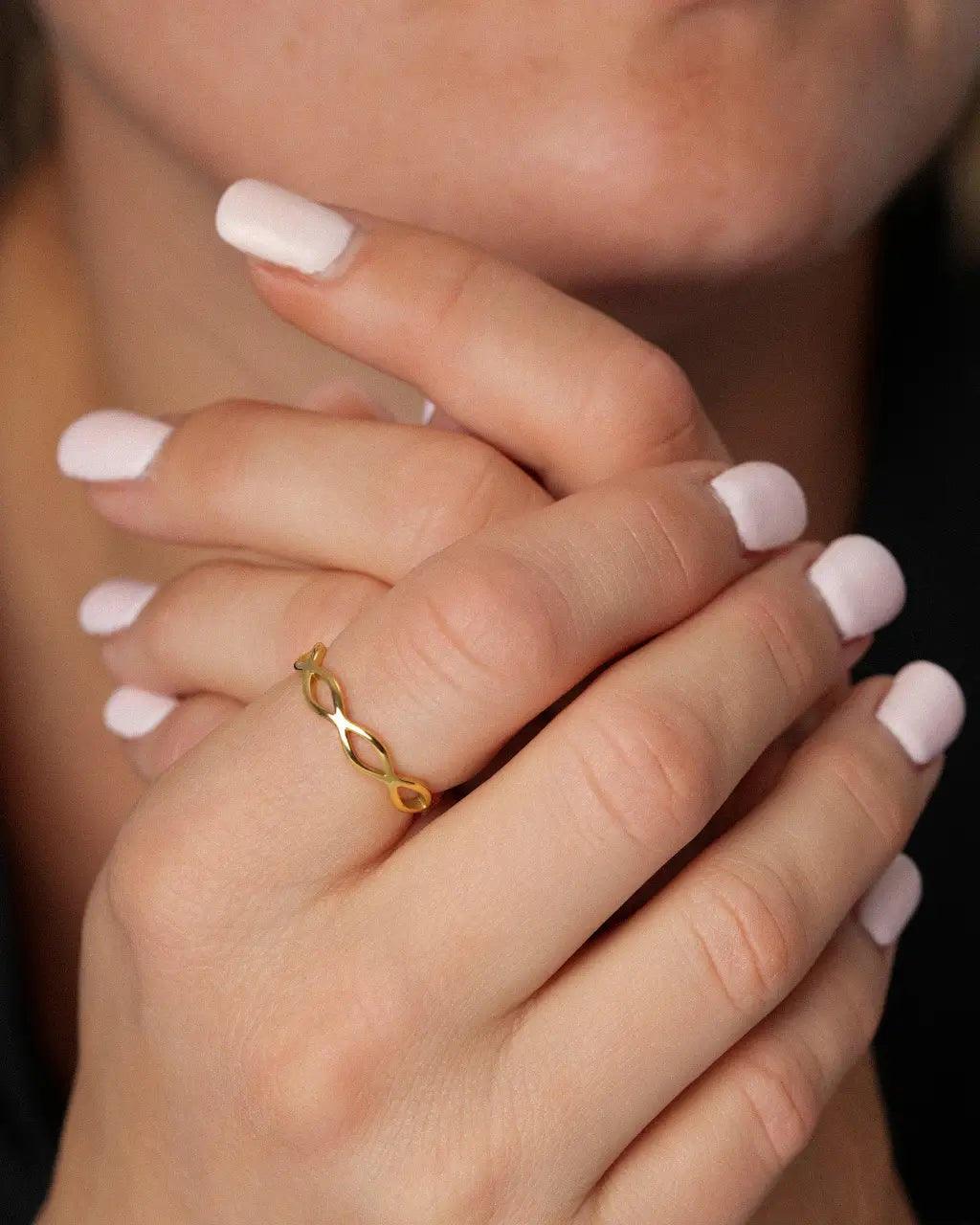 Woven Eternity Ring in gold worn on a woman's hand clasped beneath her chin